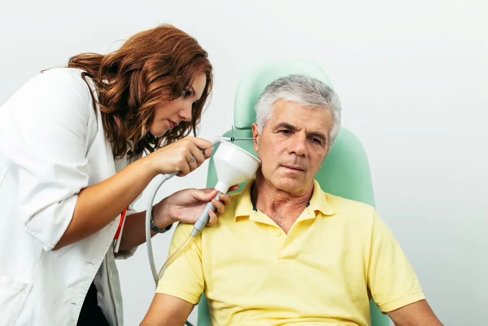Middle aged man having his ear wax removed by audiologist