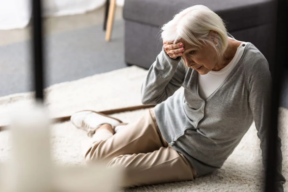 older woman sitting on carpet with her hand to her head