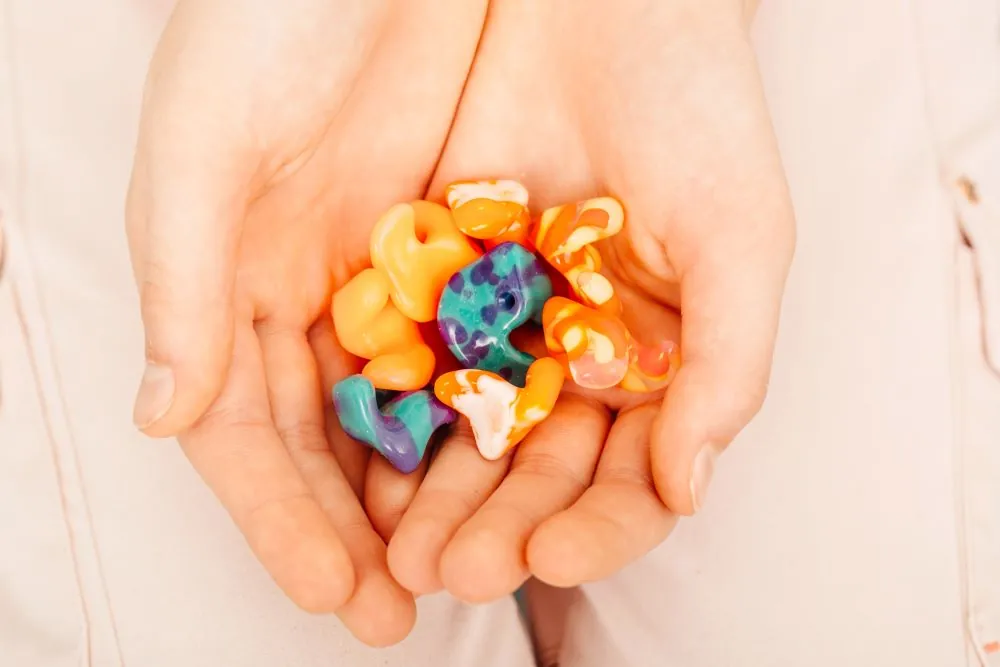 A hand holding out molded ear plugs