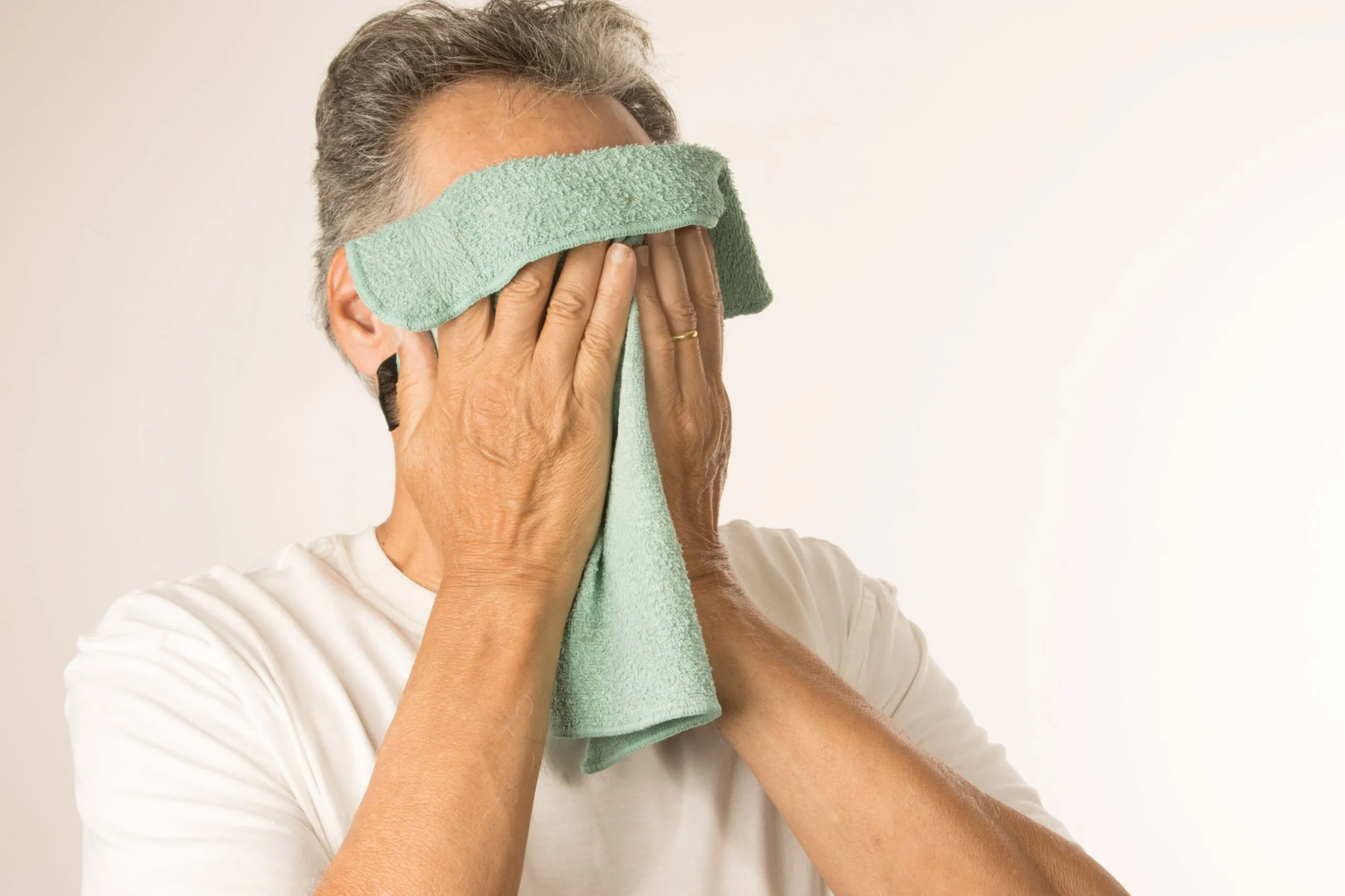 a man applying a warm compress to his face.