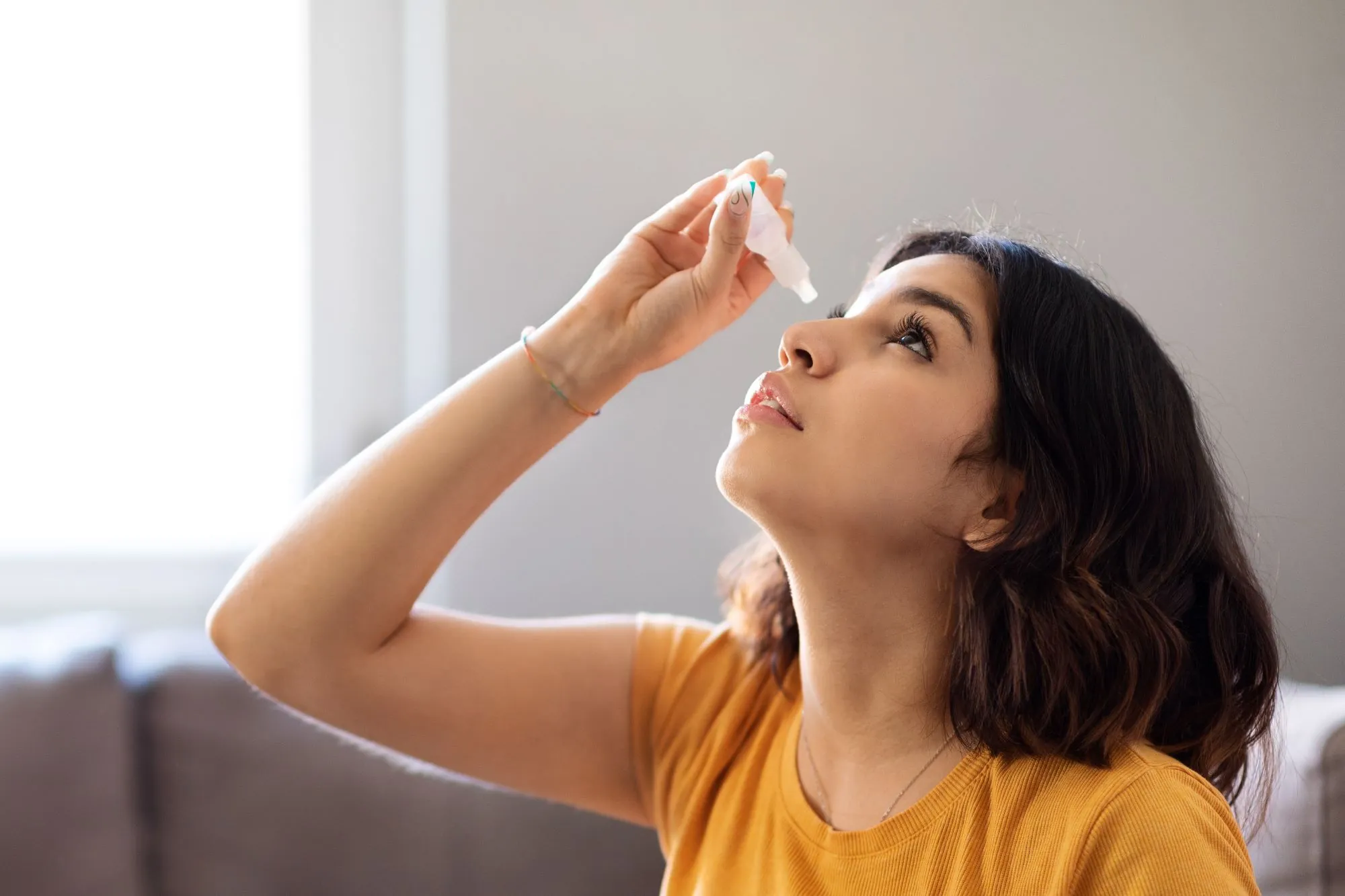 A woman putting eyedrops in her eyes